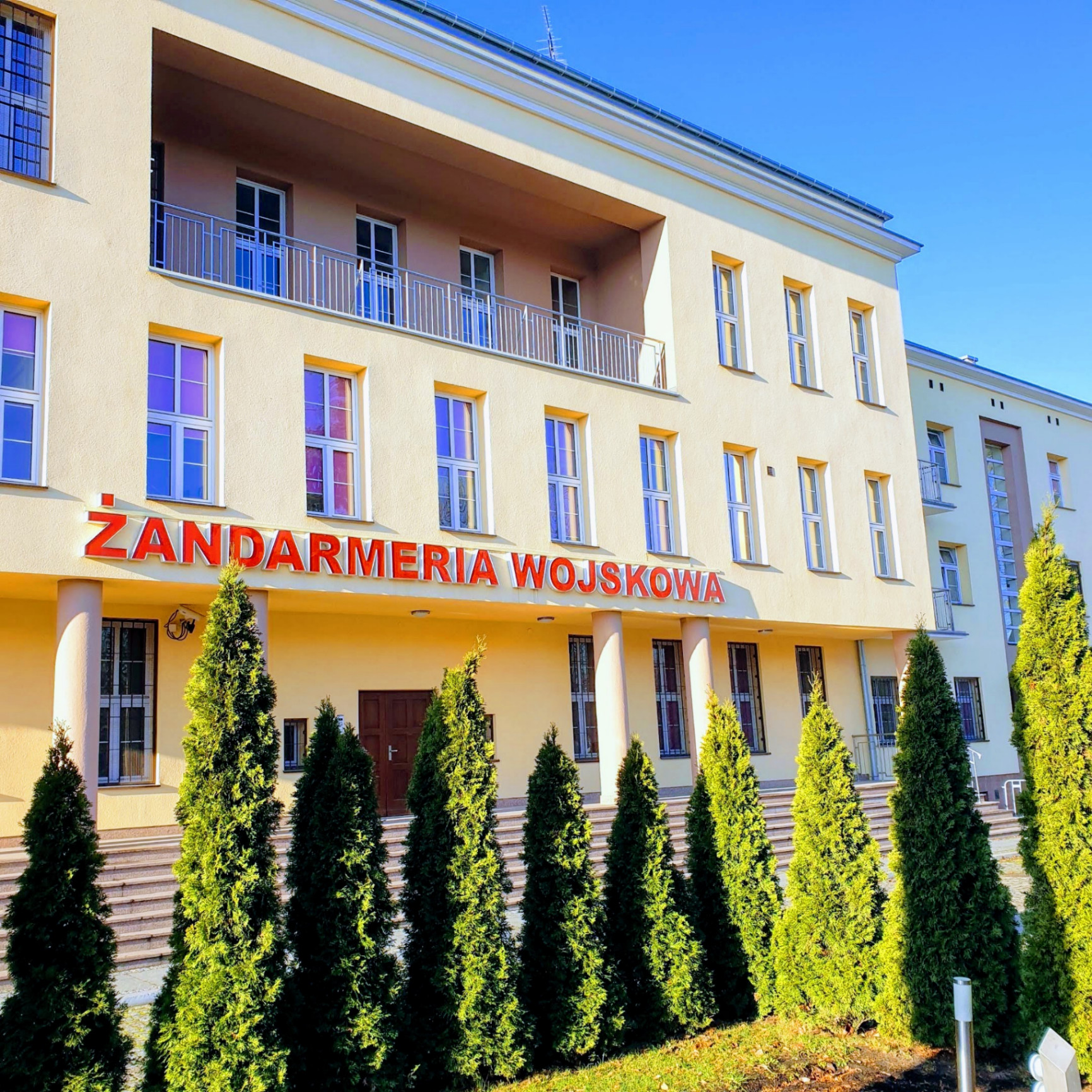 Budynek Żandarmerii Wojskowej z czerwonym napisem na elewacji — siedziba organu prowadzącego czynności wobec żołnierzy.
