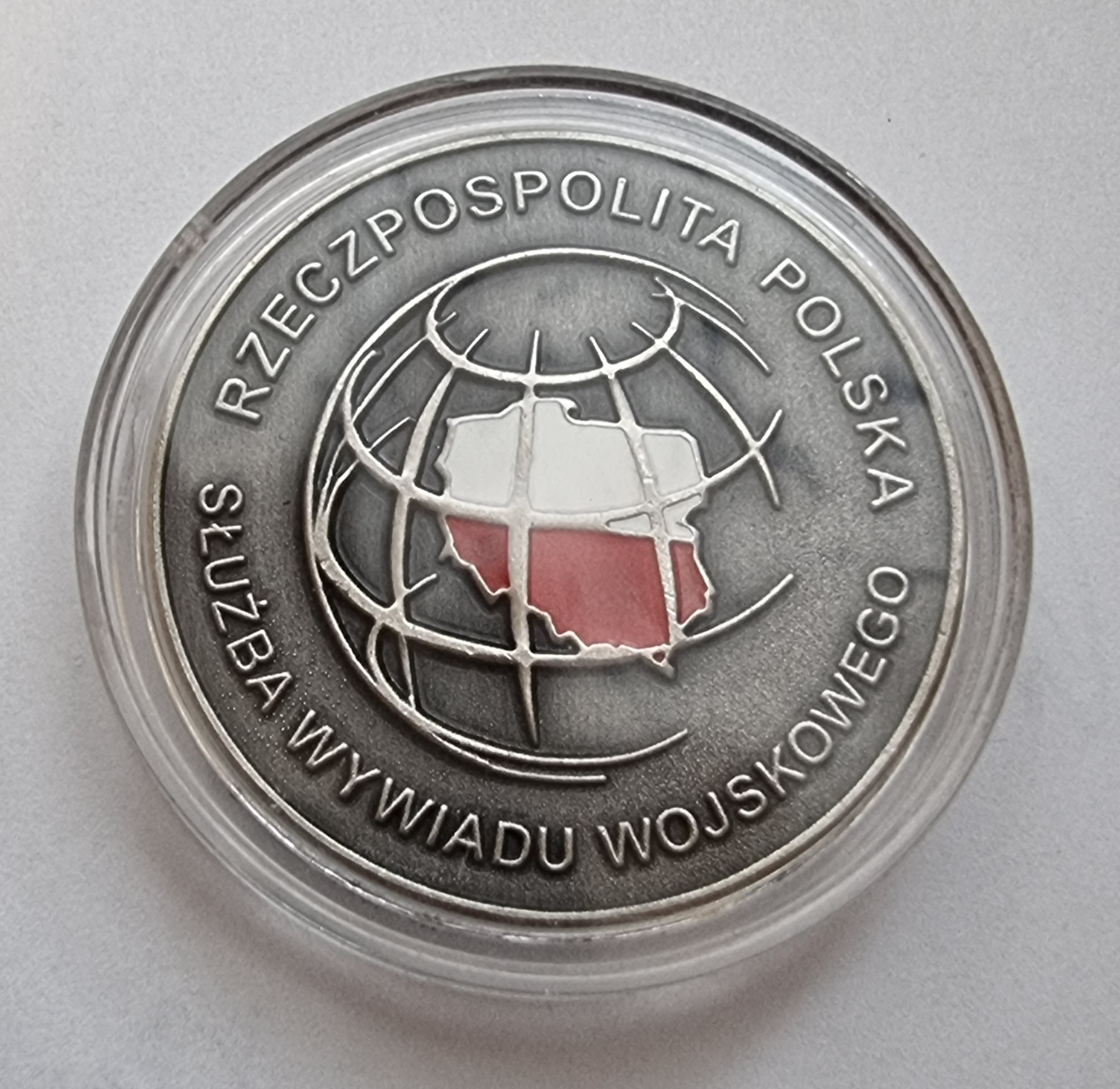Pamiątkowy medal Służby Wywiadu Wojskowego z biało-czerwoną mapą Polski na globie.