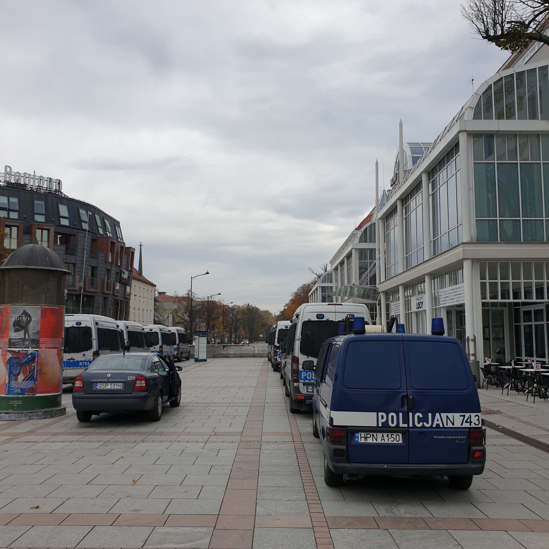 Kolumna radiowozów i busów policyjnych zaparkowanych w mieście — symbol toku postępowania dyscyplinarnego w Policji.